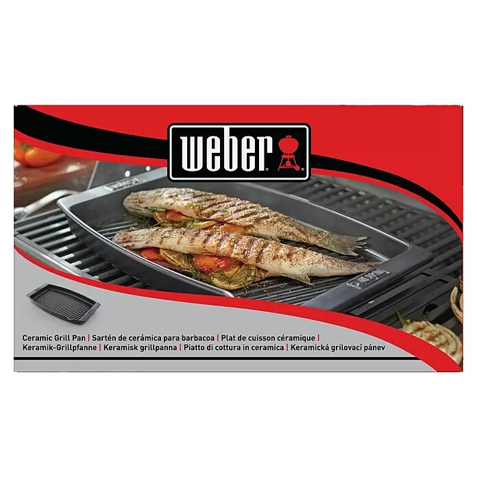 Weber Plancha - L x An: 47 x 28 cm, Altura: 4,4 cm - Sartén de cerámica negra en una parrilla, cocinando dos pescados.