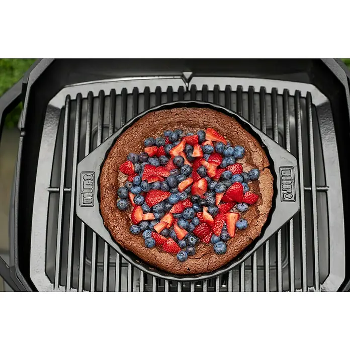 Weber Backform - Keramik - Nahaufnahme eines Weber Grills mit einem köstlichen Schokoladenkuchen, garniert mit frischen Erdbeeren und Blaubeeren.