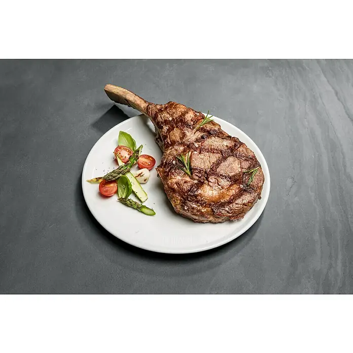 Weber Teller Porzellan - Keramik, Durchmesser: 27,5 cm - Ein appetitliches Tomahawk-Steak auf einem Teller, garniert mit frischem Gemüse. Perfekt zubereitet für ein kulinarisches Erlebnis.