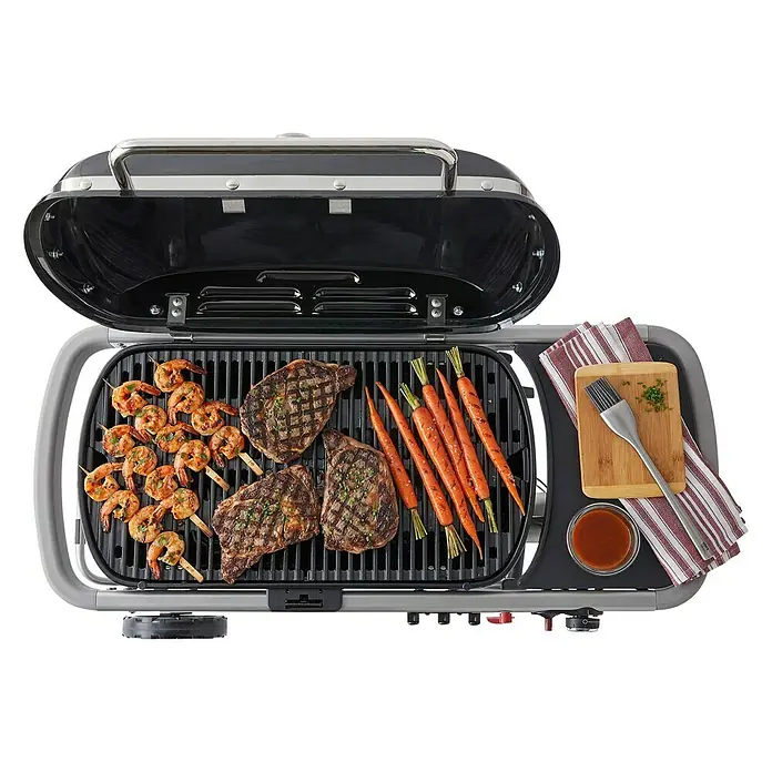 Weber Gasgrill Traveler - Grillfläche (B x T): 63 x 34 cm, 3,8 kW, Anzahl Brenner: 1, Schwarz/Silber - Grill mit Steaks, Garnelenspießen und Karotten. Das perfekte Gerät für köstliche Grillgerichte im Freien.