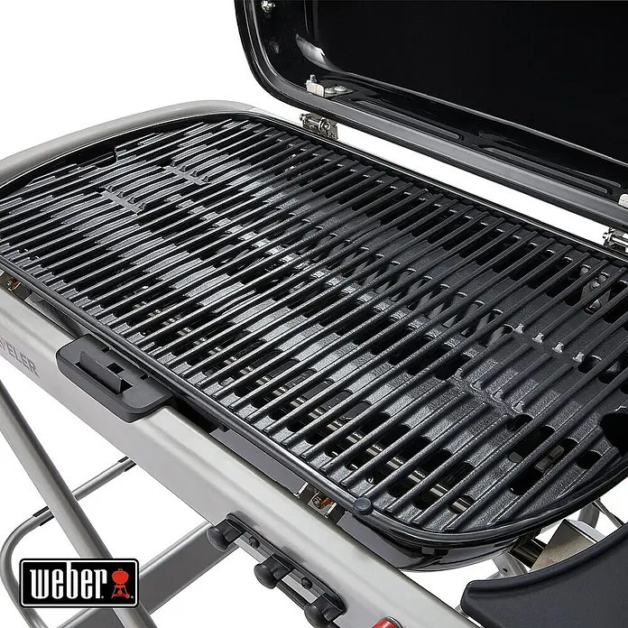 Weber Gasgrill Traveler - Grillfläche (B x T): 63 x 34 cm, 3,8 kW, Anzahl Brenner: 1, Schwarz/Silber - Nahaufnahme eines Weber Grills mit offenem Deckel, der die Grillroste zeigt. Silbernes Gestell und Weber Logo sind sichtbar.