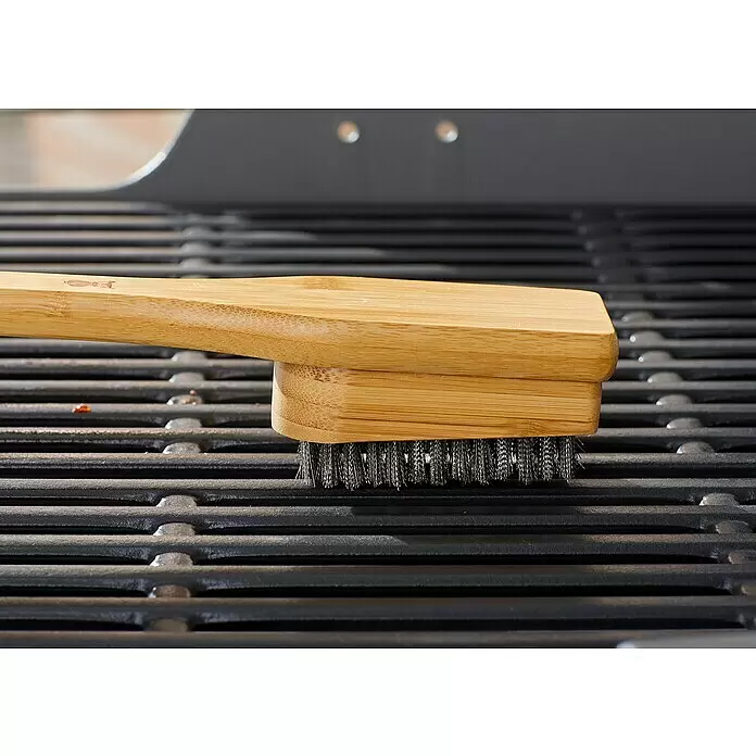 Weber Grillbürste - Länge: 44,4 cm - Holzgrillbürste mit Metallborsten auf einem schwarzen Grillrost liegend.