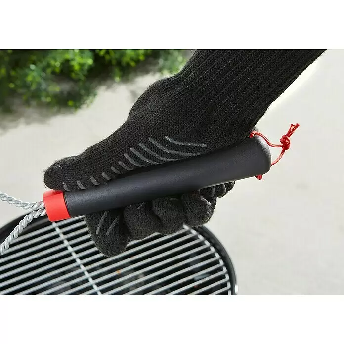 Weber Grillbürste - Länge: 30,5 cm - Hand in schwarzem Handschuh hält schwarz-roten BBQ-Pinsel mit Metallborsten über einem Grill.