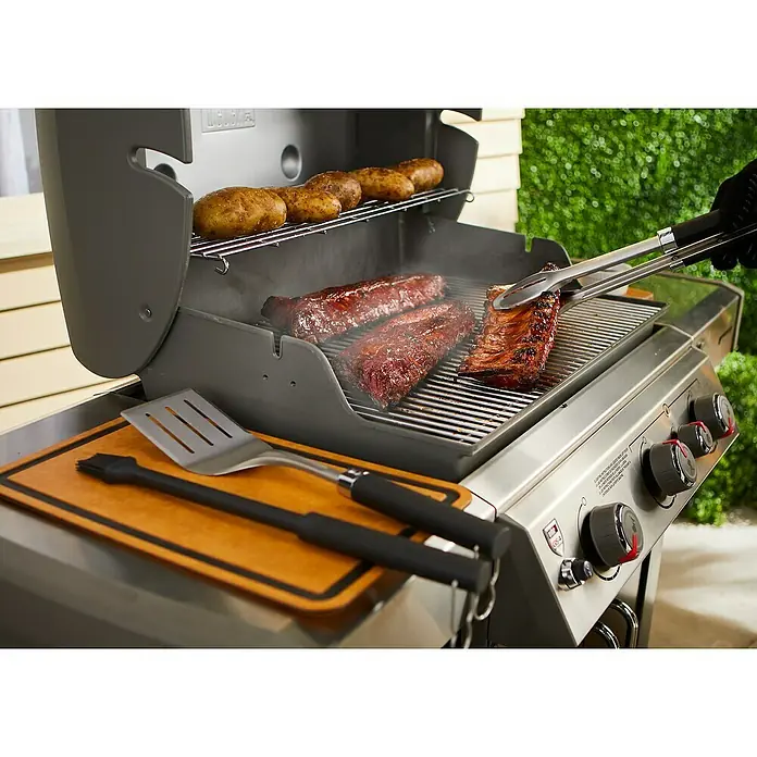 Weber Grillzubehör-Set Precision - Edelstahl - Nahaufnahme eines Weber-Grills mit Rippchen, Steaks und Kartoffeln, der ein köstliches kulinarisches Erlebnis verspricht.