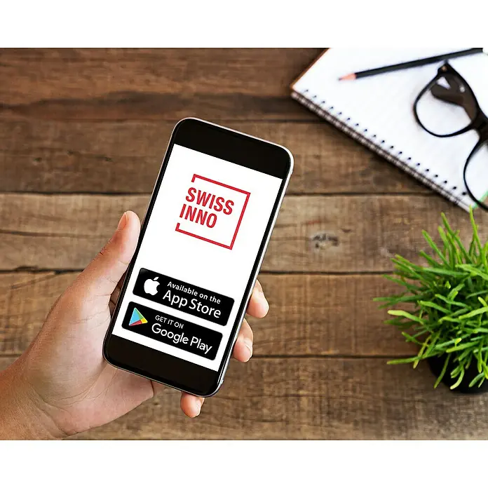 Swissinno Bluetooth-Empfangseinheit Fangalarm Connect SuperCat - Passend für: Swissinno Mause- und Rattenfallen - Smartphone mit dem Swiss Inno App-Logo auf dem Bildschirm, erhältlich im App Store und bei Google Play, auf einem Holztisch.
