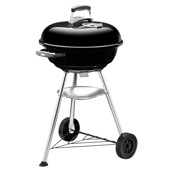 Weber Barbacoa redonda con tapa Compact Kettle - Diámetro de la superficie de la parrilla: 47 cm, Negro - Imagen de una barbacoa de carbón Weber negra con tapa, ruedas y una práctica estantería para utensilios de barbacoa.