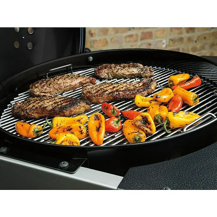 Weber Barbacoa de carbón Performer premium GBS 57 - Diámetro de la superficie de la parrilla: 57 cm, Negro - Bistecs y pimientos a la parrilla sobre una barbacoa de carbón.