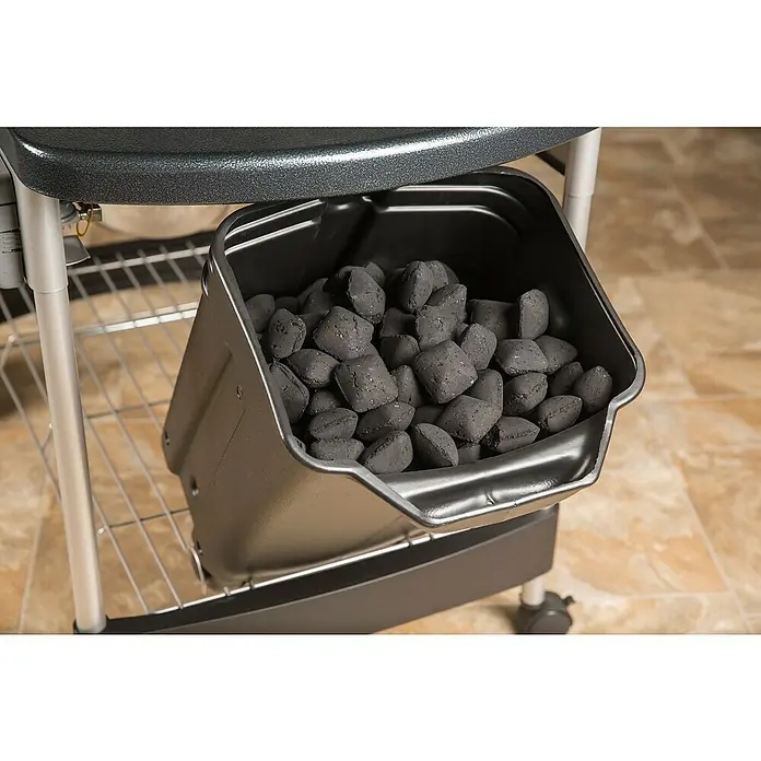 Weber Barbacoa de carbón Performer premium GBS 57 - Diámetro de la superficie de la parrilla: 57 cm, Negro - Briquetas de carbón en un recipiente debajo de una mesa de parrilla. Almacenamiento conveniente para acceso inmediato al asar al aire libre.