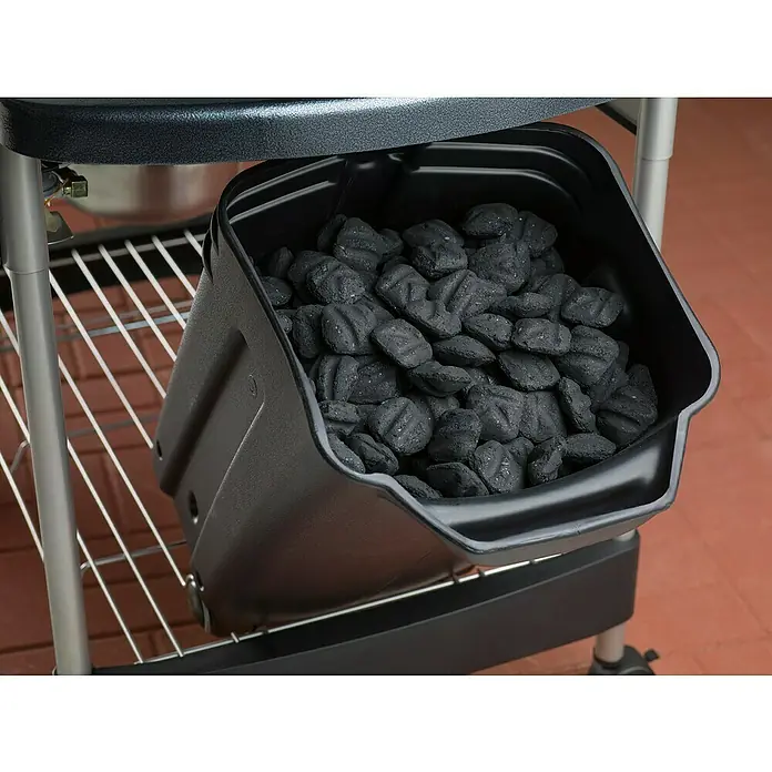 Weber Barbacoa de carbón Performer premium GBS 57 - Diámetro de la superficie de la parrilla: 57 cm, Negro - Un primer plano de una parrilla, con un contenedor lleno de briquetas de carbón, listas para asar.