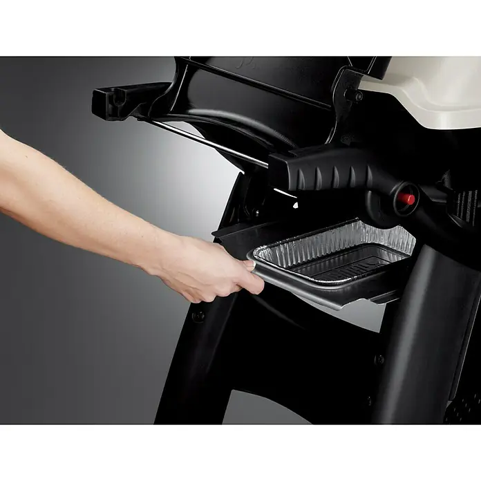 Weber Barbacoa de gas Q3000 - Superficie de la parrilla (An x Pr): 64 x 45 cm, 6,4 kW, Número de quemadores: 2 ud. - Una foto detallada muestra una parrilla con una bandeja de grasa extraíble manipulada por una mano. La bandeja está hecha de papel de aluminio.