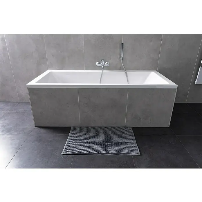 Camargue Badteppich Zottel - 50 x 80 cm, Grau, 100% Polyester - Badezimmer mit einer modernen, rechteckigen Badewanne mit grauer Verkleidung und einem passenden grauen Teppich auf dunklen Fliesen.