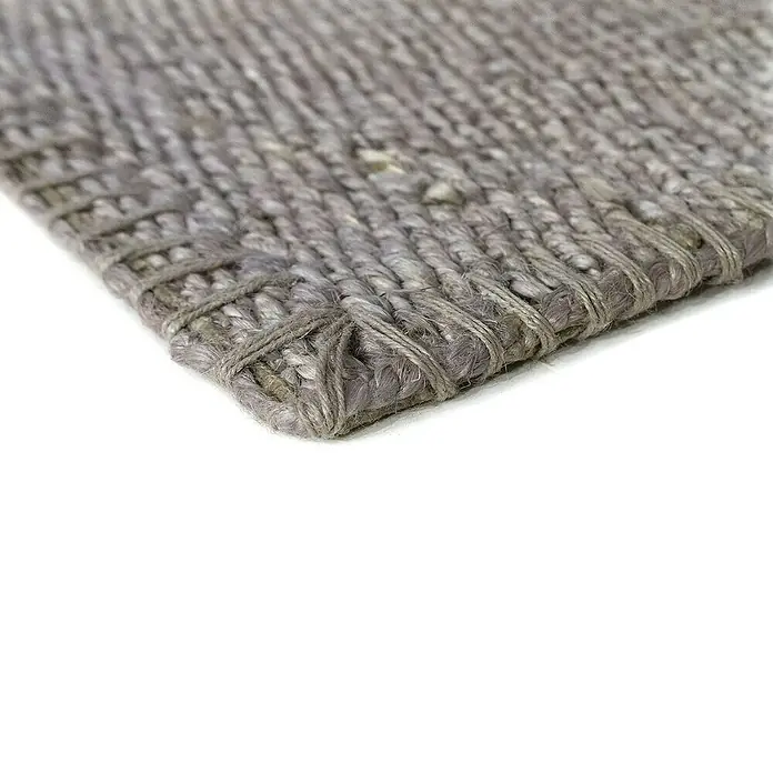 Alfombra de yute Córdoba - Gris, 230 x 160 cm, 100% yute - Primer plano de una alfombra gris tejida con una esquina visible, resaltando la textura y la construcción del producto.