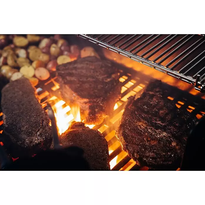 Weber Crafted Parrilla para barbacoa Sear Grate - L x An: 41,4 x 40,6 cm, Hierro fundido - Cortes de carne sazonada y papas pequeñas se cocinan en una parrilla caliente. Llamas visibles bajo las rejillas, creando un ambiente ahumado.