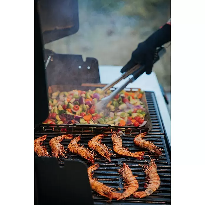 Weber Crafted Cesta para barbacoa - L x An x Al: 41 x 43 x 5 cm, Acero inoxidable - Grandes camarones se asan a la parrilla junto a coloridas verduras picadas en una bandeja, removidas por una mano enguantada con pinzas.