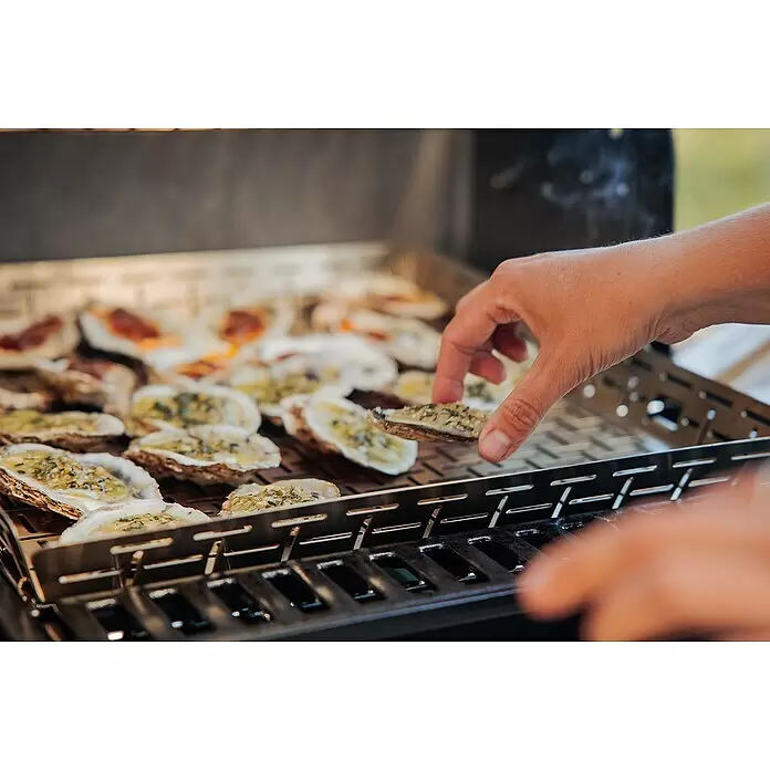 Weber Crafted Cesta para barbacoa - L x An x Al: 41 x 43 x 5 cm, Acero inoxidable - Bandeja metálica para ostras a la parrilla, una mano colocando una ostra sazonada; muchas ya cocinándose.