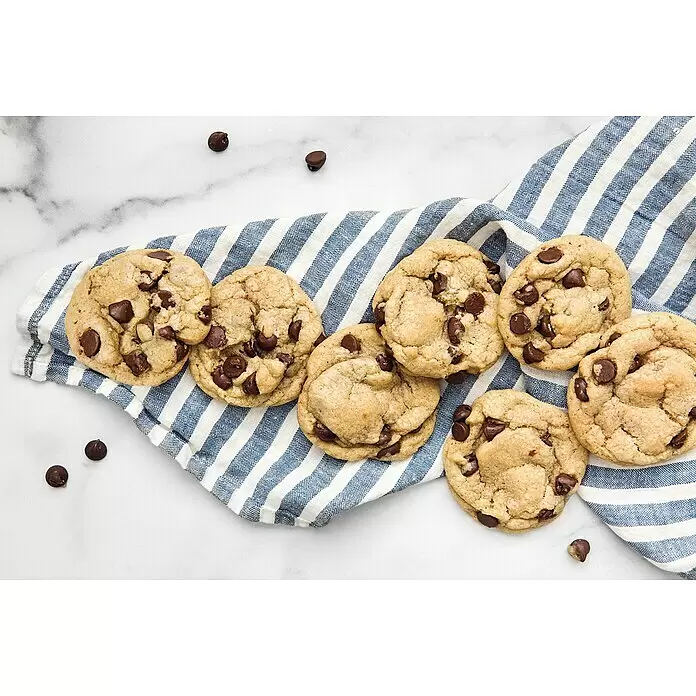 Weber Crafted Piedra para pizzas Esmaltado - L x An: 41,4 x 40,6 cm - Galletas de chocolate doradas con trozos de chocolate, sobre un paño a rayas azules y blancas, con trozos de chocolate sueltos.