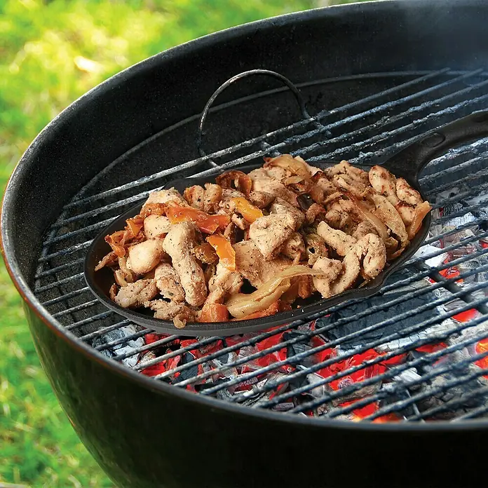 Jim Beam Pfannen-Set - 3 -tlg., Holz - Eine gusseiserne Grillpfanne auf einem Holzkohlegrill mit gegrilltem Hähnchen, Zwiebeln und Paprika, ideal für Fajitas oder andere Grillgerichte.