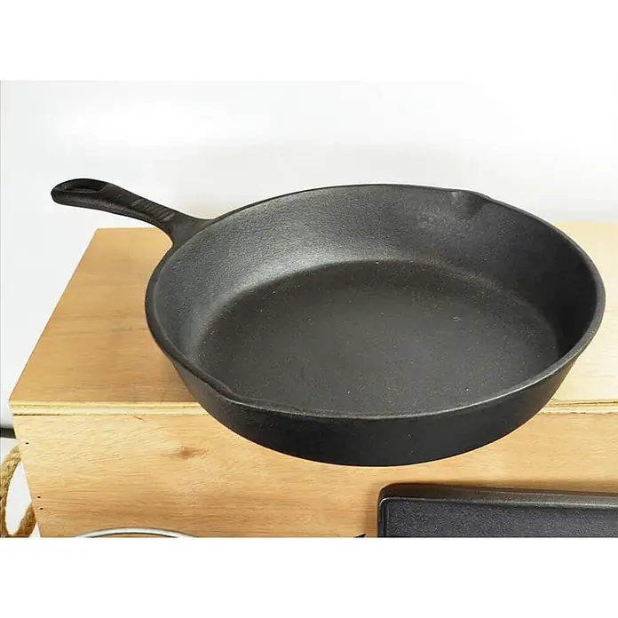 Jim Beam Koch-Set - 9 -tlg., Schwarz - Eine schwarze gusseiserne Bratpfanne mit Griff, die auf einer Holzoberfläche steht und bereit für kulinarische Abenteuer ist.