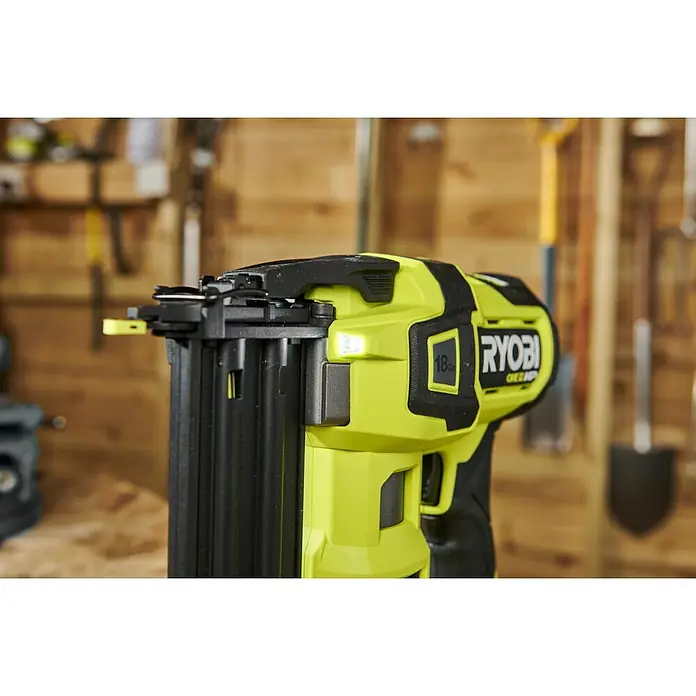Ryobi ONE+ Akku-Nagler R18GN18X-0 - 18 V, Ohne Akku, Länge Nagel: 15 mm - 54 mm - Nahaufnahme eines RYOBI Akku-Nagelgeräts vor einer hölzernen Werkstattwand mit Werkzeugen.