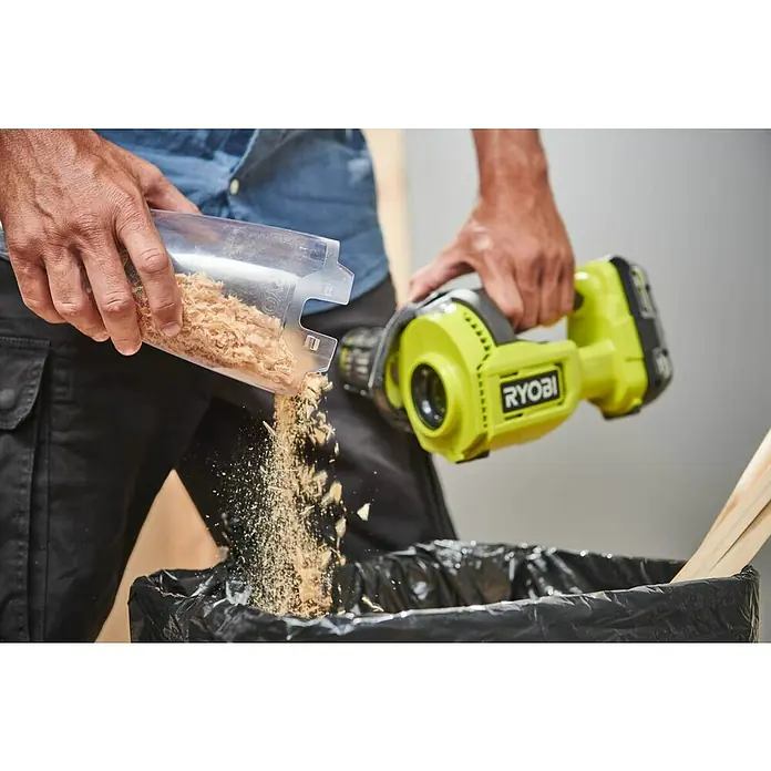 Ryobi ONE+ Akku-Handstaubsauger RHV18-0 - 18 V, Ohne Akku, Behältervolumen: 0,6 l - Ein Mann entleert einen transparenten Behälter mit Holzspänen in einen schwarzen Müllsack, während er einen gelben Ryobi-Staubsauger hält.