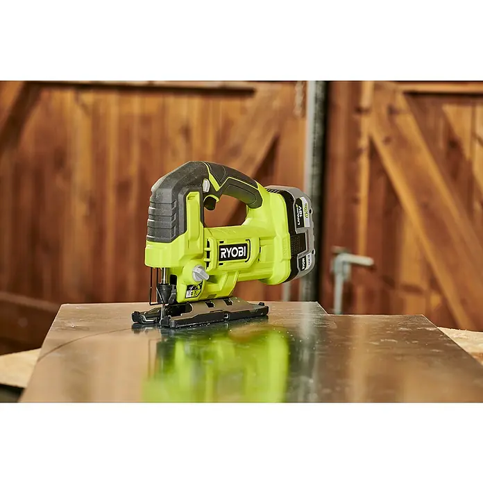 Ryobi ONE+ Akku-Pendelhubstichsäge RJS18-0 - 18 V, Ohne Akku - Akkustichsäge von Ryobi, ideal für präzise Holzarbeiten, auf einer glänzenden Oberfläche platziert, mit Holz im Hintergrund.