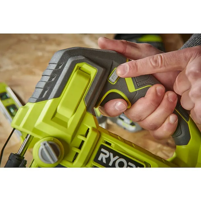 Ryobi ONE+ Akku-Pendelhubstichsäge RJS18-0 - 18 V, Ohne Akku - Nahaufnahme eines Ryobi-Elektrowerkzeugs mit einer Hand, die einen Knopf drückt, was die Details und Funktionalität des Werkzeugs hervorhebt.