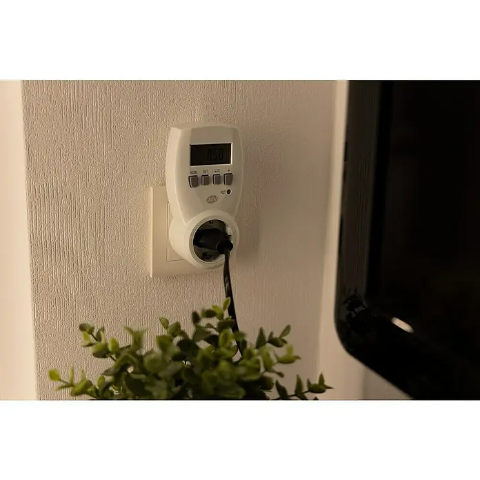Energiekosten-Messgerät Digital - 3.680 W - Ein weißer Stromverbrauchsmesser von REV steckt in einer Steckdose an einer Wand, wobei ein schwarzes Kabel hineinführt.