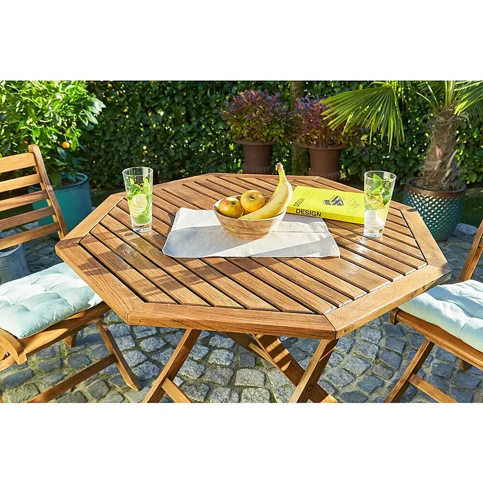 swingcolor Teak-Öl - Teak, 750 ml, Seidenmatt - Ein Gartentisch-Set aus Holz mit Obstschale und Getränken, umgeben von grünen Pflanzen im Hintergrund. Ideal für den Garten!