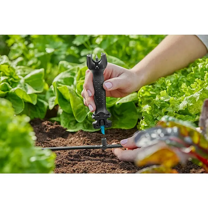 Gardena Micro-Drip Pieza T - ³⁄₁₆'', 10 ud. - Una persona utiliza una herramienta para instalar un sistema de riego en un huerto.