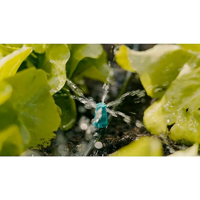 Gardena Micro-Drip Aspersor para pequeñas superficies - 15 ud. - Primer plano de una boquilla de riego rociando agua sobre plantas de lechuga verdes, ideal para el riego del jardín y el cuidado de plantas.