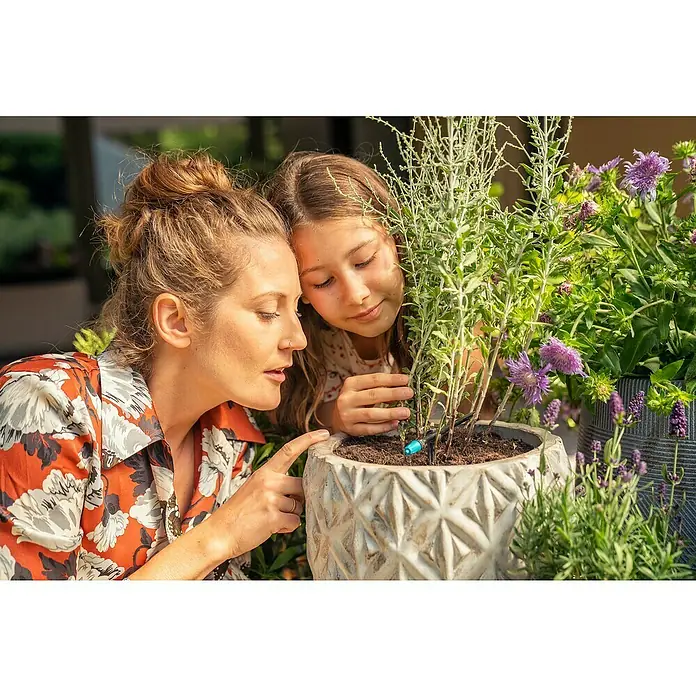 Gardena Micro-Drip Aspersor para pequeñas superficies - ½″, 15 ud. - Madre e hija admiran una planta en maceta con lavanda y flores que está siendo regada. El sistema de riego es la estrella de la imagen.