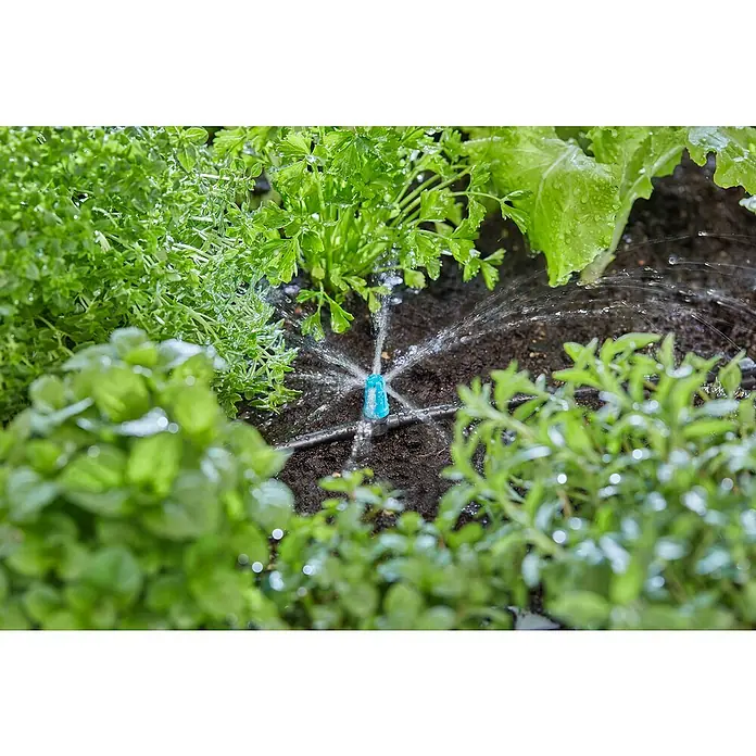 Gardena Micro-Drip Aspersor para pequeñas superficies - ½″, 15 ud. - Primer plano de un aspersor de riego, irrigando plantas en un jardín con exuberante vegetación, asegurando la hidratación.