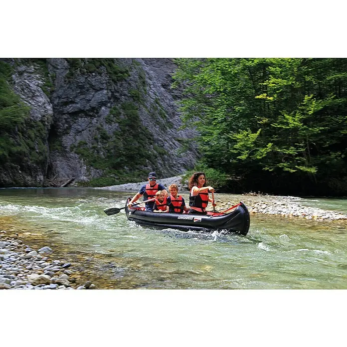 Grabner Kanu Adventure - L x B: 450 x 95 cm, Nutzlast: 450 kg, Geeignet für: 3 Personen - Familie genießt eine Fahrt mit einem aufblasbaren Abenteuerkanu auf einem Fluss, umgeben von üppiger Natur und felsigen Klippen.
