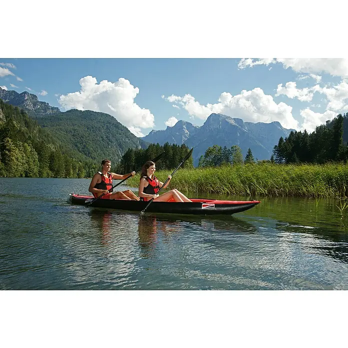 Grabner Kajak Tramper - L x B: 400 x 90 cm, Nutzlast: 200 kg, Geeignet für: 2 Personen - Ein rotes und schwarzes Schlauchboot mit zwei Personen darauf, die auf einem See mit Bergen im Hintergrund paddeln.