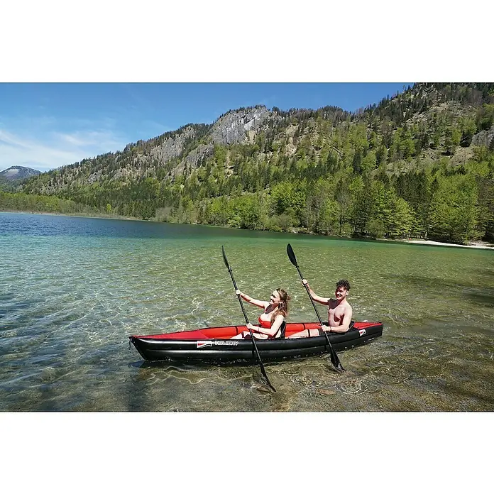 Grabner Kajak Holiday 2 - L x B: 395 x 75 cm, Nutzlast: 190 kg, Geeignet für: 2 Personen - Ein aufblasbares rotes und schwarzes Kajak mit zwei Personen auf einem klaren See, umgeben von bewaldeten Bergen.