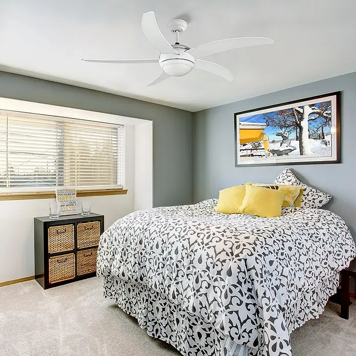 Arte confort Ventilador de techo Tahiti - Blanco, 132 cm, 65 W - Un moderno ventilador de techo blanco con cinco aspas destaca en un dormitorio con paredes grises y colcha estampada.