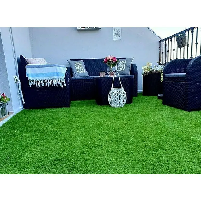 Césped artificial Bahia - 5 x 2 m, Altura del pelo: 18 mm, 26.250 puntadas/m² - Un acogedor espacio exterior con césped artificial, muebles de ratán y elementos decorativos que crean un ambiente relajante.