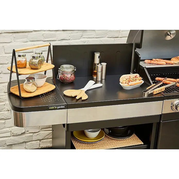 Mueble auxiliar modular para barbacoa Fidgi - Negro/Plateado - Primer plano de una parrilla Cook'in Garden con especias, salsas y comida a la parrilla, lista para una deliciosa experiencia de barbacoa al aire libre.