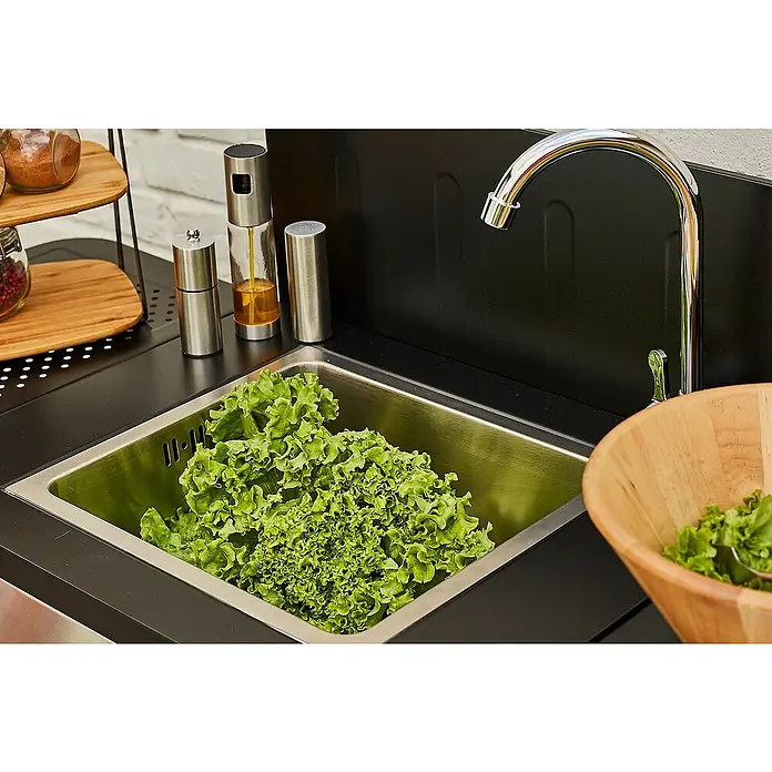 Mueble auxiliar lavadero modular para barbacoa Fidgi - Negro/Plateado - Un fregadero de acero inoxidable lleno de lechuga fresca, un tazón para ensalada y utensilios en una isla.