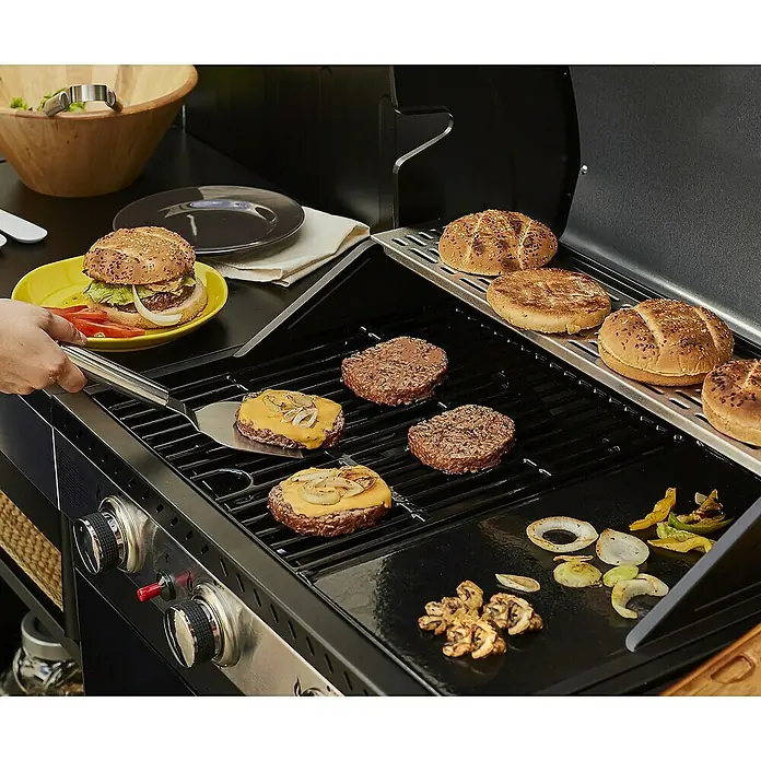 Barbacoa de gas Fidgi - Superficie de la parrilla (An x Pr): 57,5 x 42 cm, 11,5 kW, Número de quemadores: 3 - Una parrilla con ingredientes para hamburguesas. En la parrilla se preparan hamburguesas, queso y verduras, y se calientan los panes.
