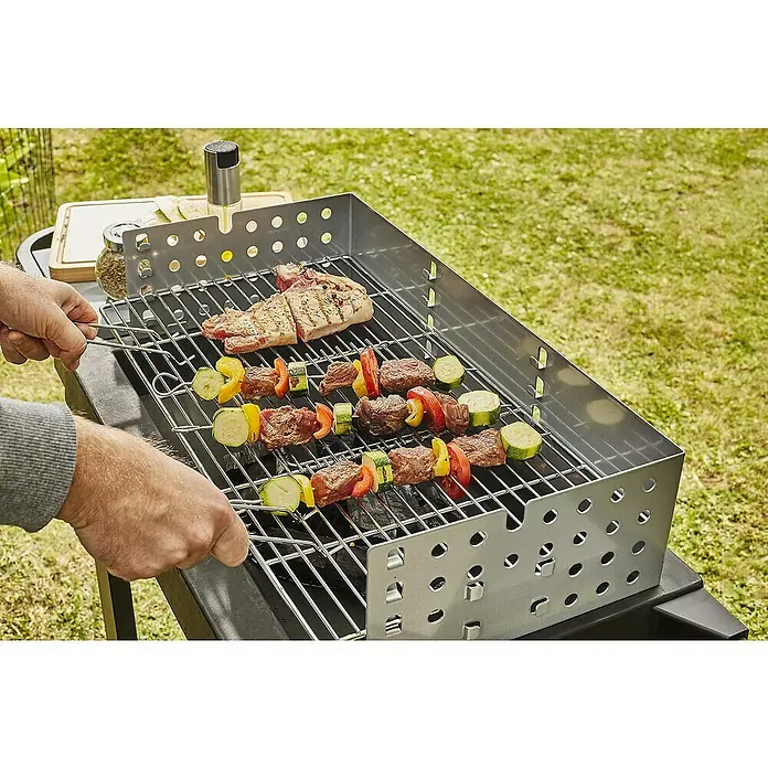 Barbacoa de carbón Easy 60 - Superficie de la parrilla (An x Pr): 57 x 30 cm, Negro - Una vista de una parrilla con deliciosos pinchos de carne y un filete jugoso, perfecto para una barbacoa al aire libre con familiares y amigos.