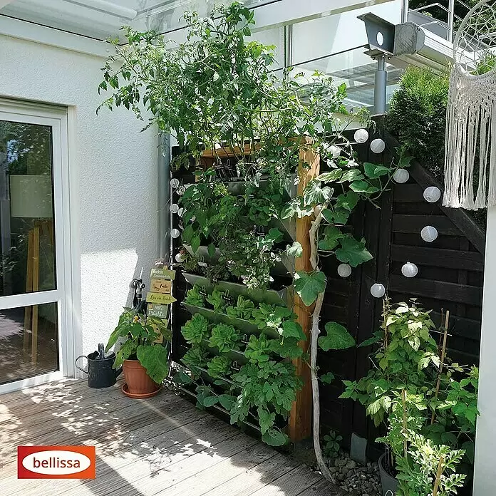 Bellissa Hochbeet Inalto L8 - 100 x 32 x 180 cm, Stahl, Hellbraun/Silber - Vertikales Gartensystem mit Holzrahmen und Metallpflanzgefäßen, bepflanzt auf einer sonnigen Terrasse.