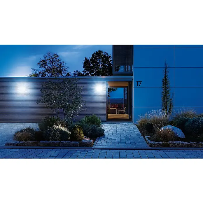 Steinel LED-Sensor-Strahler XLED home 2 S graphit - 13,7 W, L x B x H: 161 x 180 x 218 mm, Graphit, IP44 - Ein modernes Haus mit Außenbeleuchtung, die die Fassade und den Vorgarten hervorhebt. Die Hausnummer 17 ist gut sichtbar.