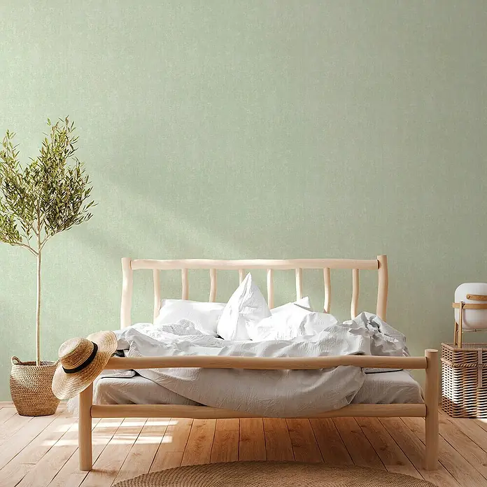 A.S. Création Hygge 2 Vliestapete - Grün/Schwarz, Uni, 10,05 x 0,53 m - Helles Schlafzimmer mit hellem Holzrahmenbett, weißer Bettwäsche, einem kleinen Baum und einem Strohhut.