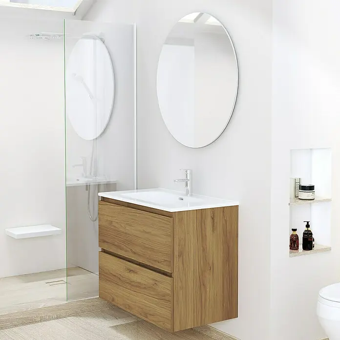 Artysan Conjunto de mueble de baño Basic 2C - Ancho: 70 cm, Ancho total del mueble de baño: 70 cm, Roble waira, 3 pzs. - Un tocador moderno con un acabado de veta de madera y dos cajones, situado debajo de un espejo redondo en un baño luminoso.
