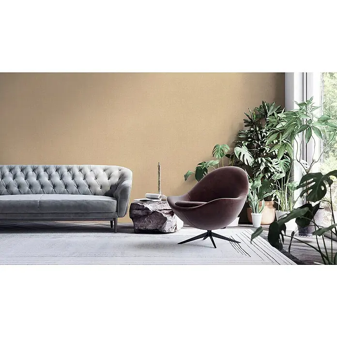 A.S. Création My Home My Spa Vliestapete - Beige/Metallic, Uni, 10,05 x 0,53 m - Ein elegantes Wohnzimmer mit einem grauen Sofa, einem braunen Sessel und vielen Zimmerpflanzen, die eine gemütliche Atmosphäre schaffen.