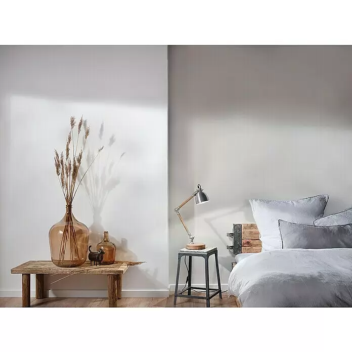 A.S. Création Mata Hari Vliestapete - Cremebeige, Uni, 10,05 x 0,53 m - Rustikal-industrielles Schlafzimmer mit Holzbank, Amberflaschen, getrocknetem Gras und grauem Leinenbett.
