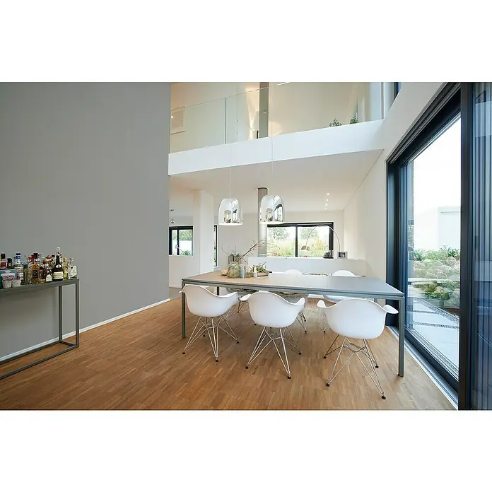 A.S. Création My Home My Spa Vliestapete Textstruktur I - Dunkelgrau, Uni, 10,05 x 0,53 m - Ein modern eingerichteter Raum mit Esstisch und Stühlen, beleuchtet von stilvollen Pendelleuchten, betont durch ein großes Fenster mit Blick ins Grüne.