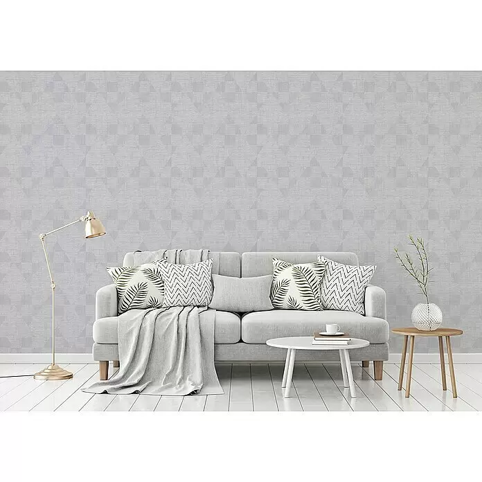 A.S. Création Titanium 3 Vliestapete - Silbergrau, Grafisch, 10,05 x 0,53 m - Hellgraue Tapete mit dezentem geometrischem Muster aus Quadraten und Dreiecken an einer Wohnzimmerwand hinter einem Sofa.