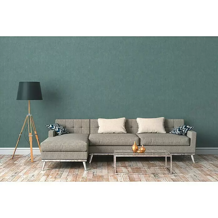 A.S. Création Cuba Vliestapete - Blau/Grün, Uni, 10,05 x 0,53 m - Ein bequemes graues Stoff-Ecksofa mit Metallbeinen und getufteter Rückenlehne in einem modernen Wohnzimmer.